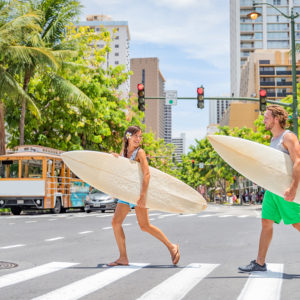 two persons carrying their surfboard