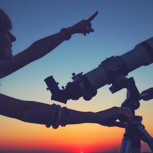 Girl looking at the stars with telescope beside her. Maui stargazing and astronomy tours
