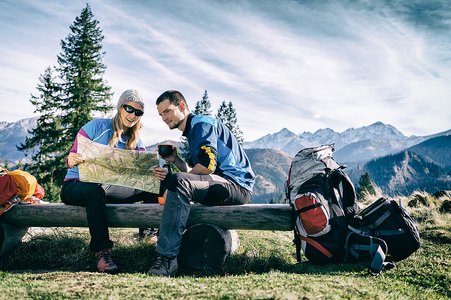 Man and woman hikers hiking in mountains. Young couple camping looking at map and planning trip to Pipiwai Trail Hiking